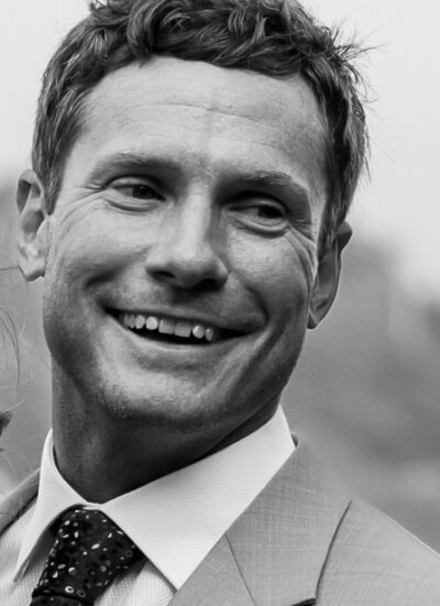 A photo headshot of Benjamin Ryan. He is wearing a suit and smiling.