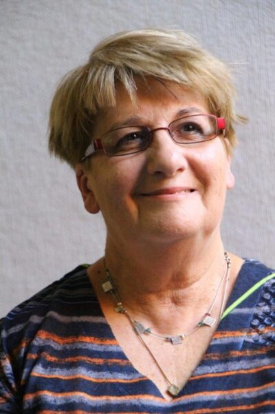 A portrait of Judith Buckrich. She is a blonde woman with pale skin and glasses