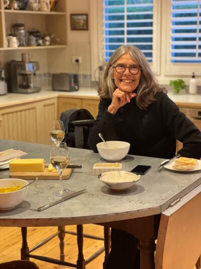 An image of Kate Legge. She sits at a table with her head leaning on her fist.