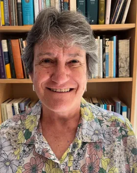 A photo of Judith Beveridge. She stands in front of a bookshelf.