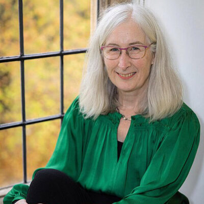 Historian Lyndal Roper sitting on a windowsill.